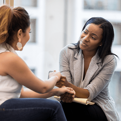 female therapist holds woman's hand
