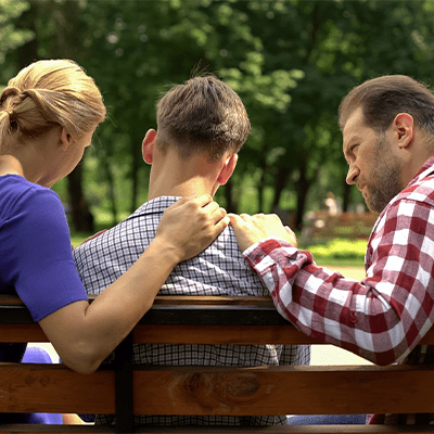 white-mother-and-father-with-son-on-park-bench